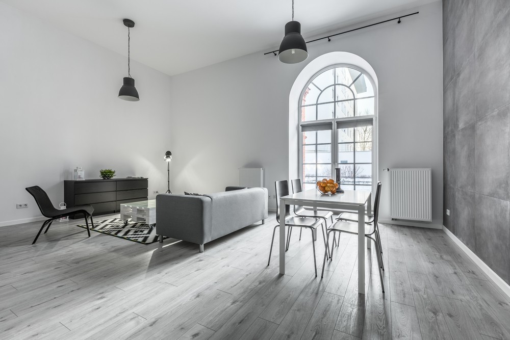 Salon z szarą podłogą i dużym oknem - naturalne światło i nowoczesny design.