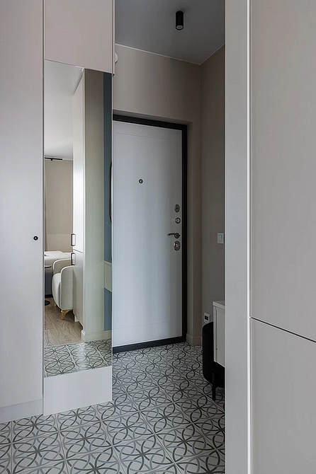 Ciemnoszara podłoga w przedpokoju z lustrem i wieszakiem na ubrania. Praktyczne rozwiązanie.