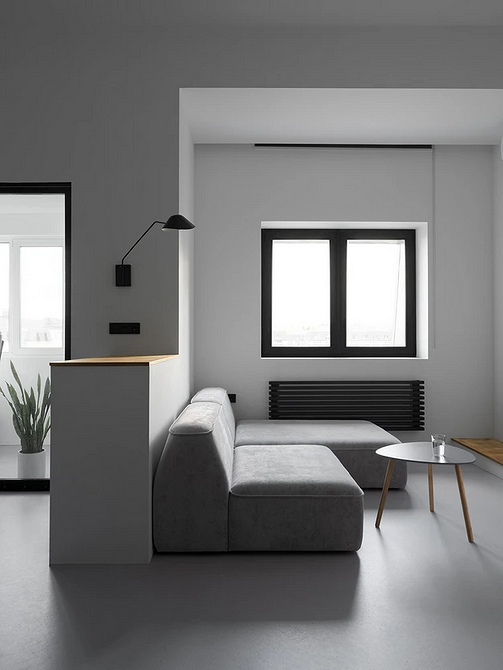 Monochromatyczna aranżacja wnętrza z szarą podłogą, ścianami i meblami w odcieniach szarości.