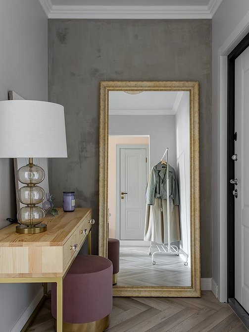 Przestronny salon z szarą podłogą, dywanem w geometryczne wzory i kolorowymi dodatkami.