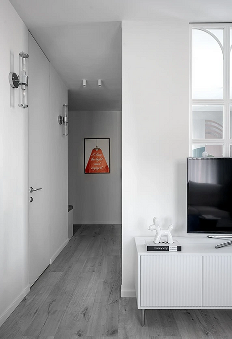 Szara podłoga w małym mieszkaniu z jasnymi ścianami i kolorowymi dodatkami.